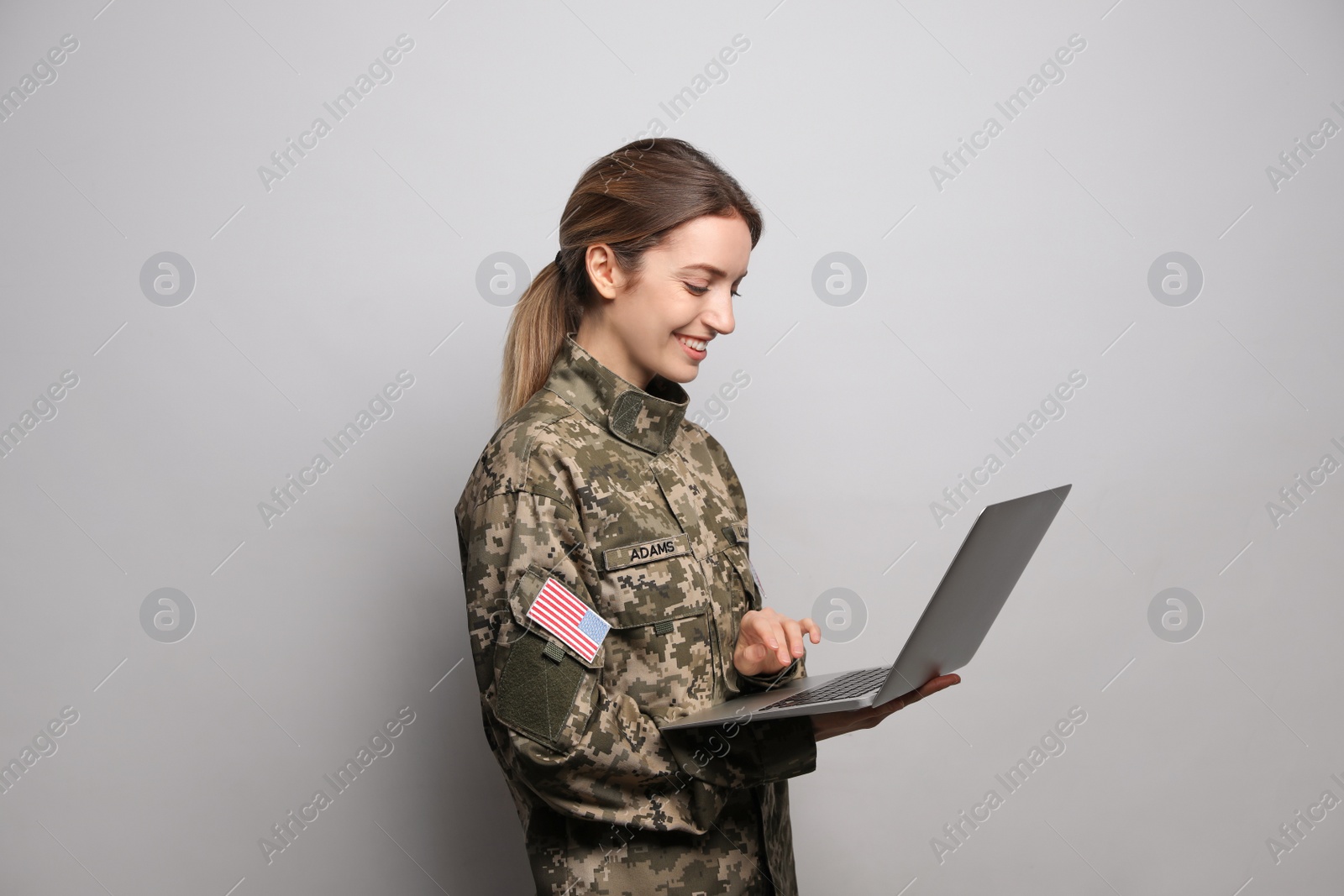 Photo of Female cadet with laptop on light grey background. Military education