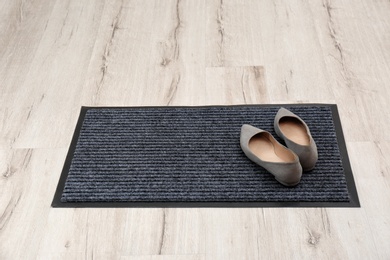 Photo of New clean doormat with shoes on floor. Space for text