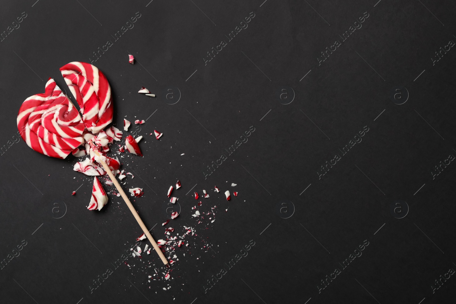 Photo of Broken heart shaped lollipop on black background, top view with space for text. Relationship problems concept