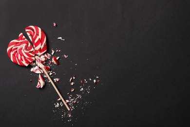 Photo of Broken heart shaped lollipop on black background, top view with space for text. Relationship problems concept