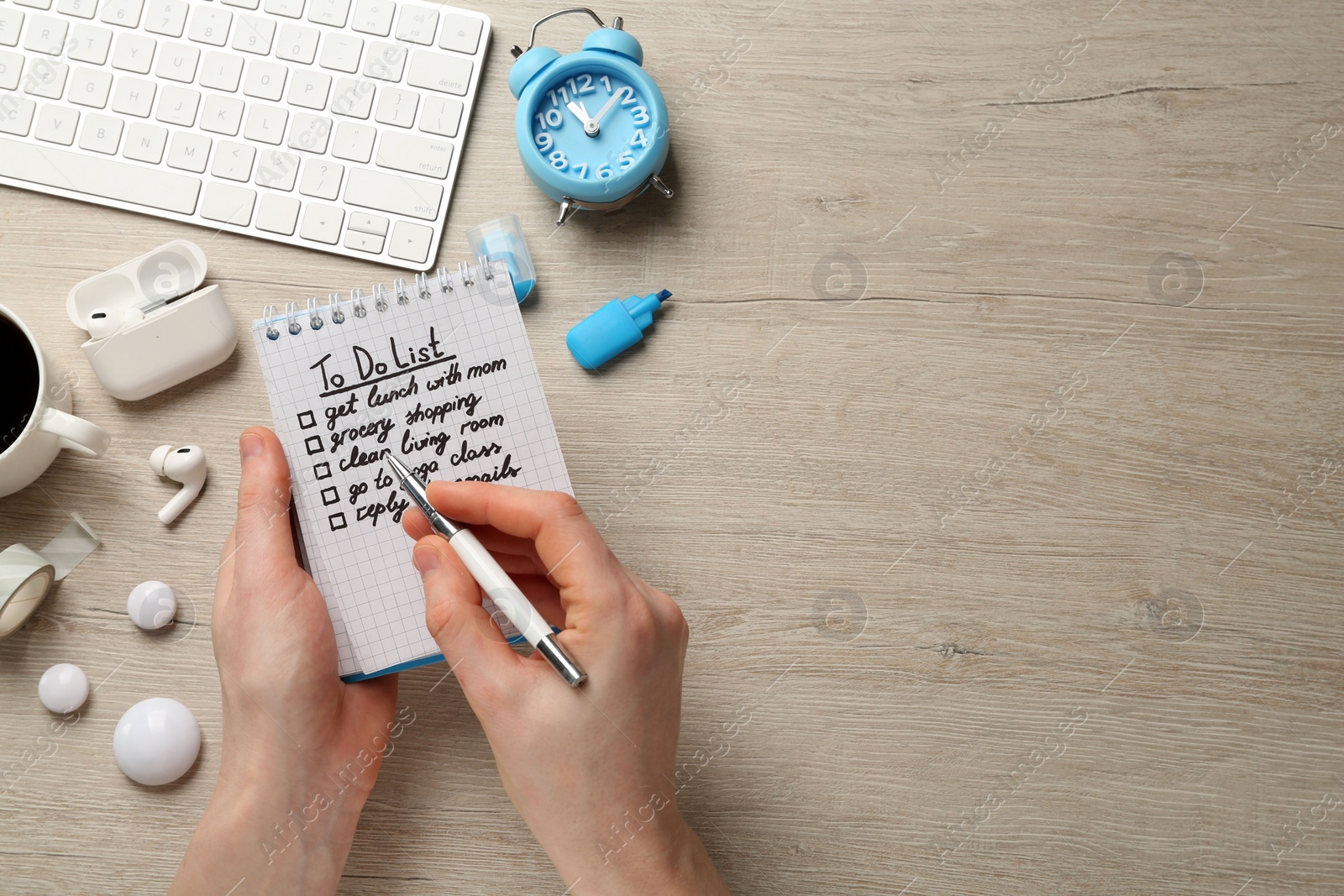 Photo of Woman checking to do list at white wooden table, top view. Space for text