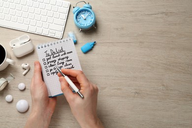 Photo of Woman checking to do list at white wooden table, top view. Space for text