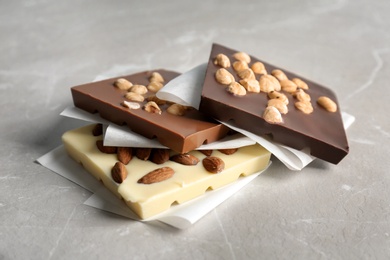 Photo of Different chocolate bars with nuts on grey background
