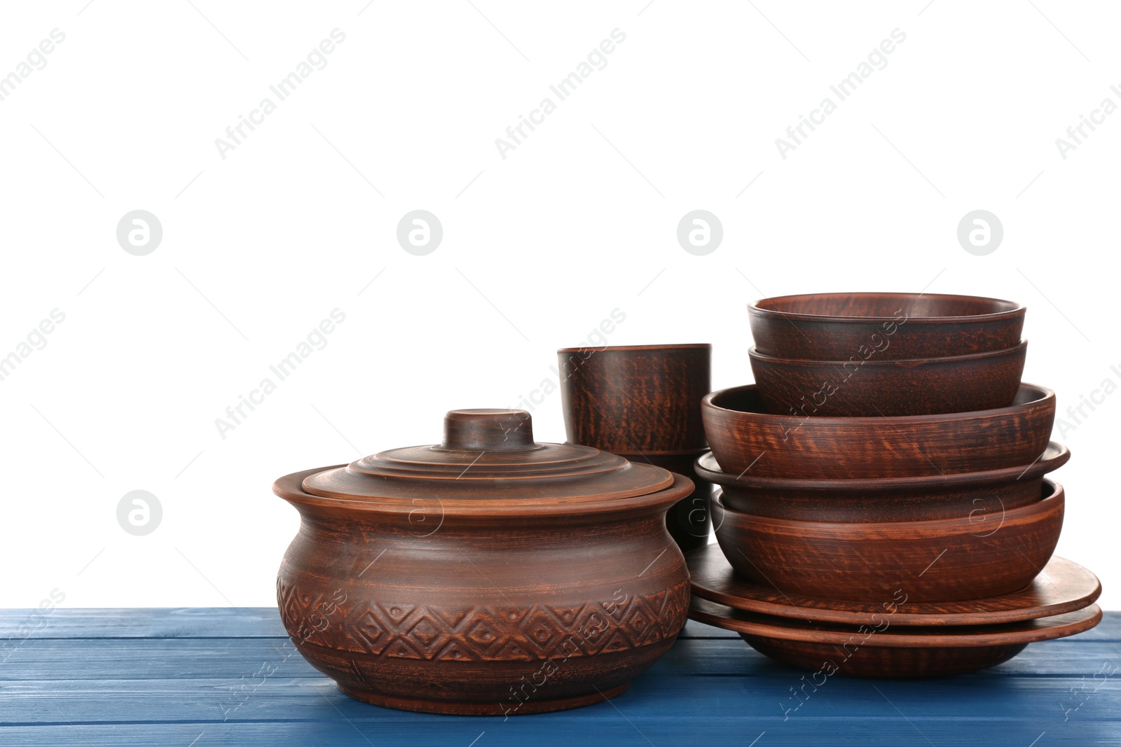 Photo of Set of clay dishes on blue wooden table against white background