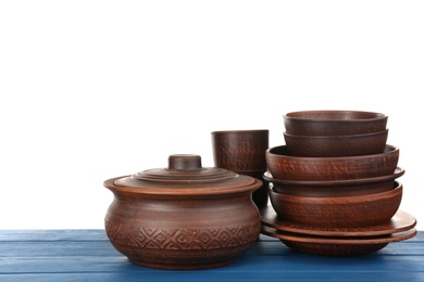 Photo of Set of clay dishes on blue wooden table against white background