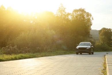 Photo of Black modern car on paved road at sunset, space for text