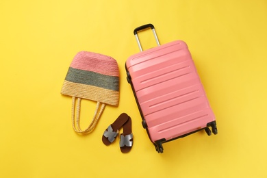 Photo of Stylish suitcase, beach bag and shoes on color background, top view