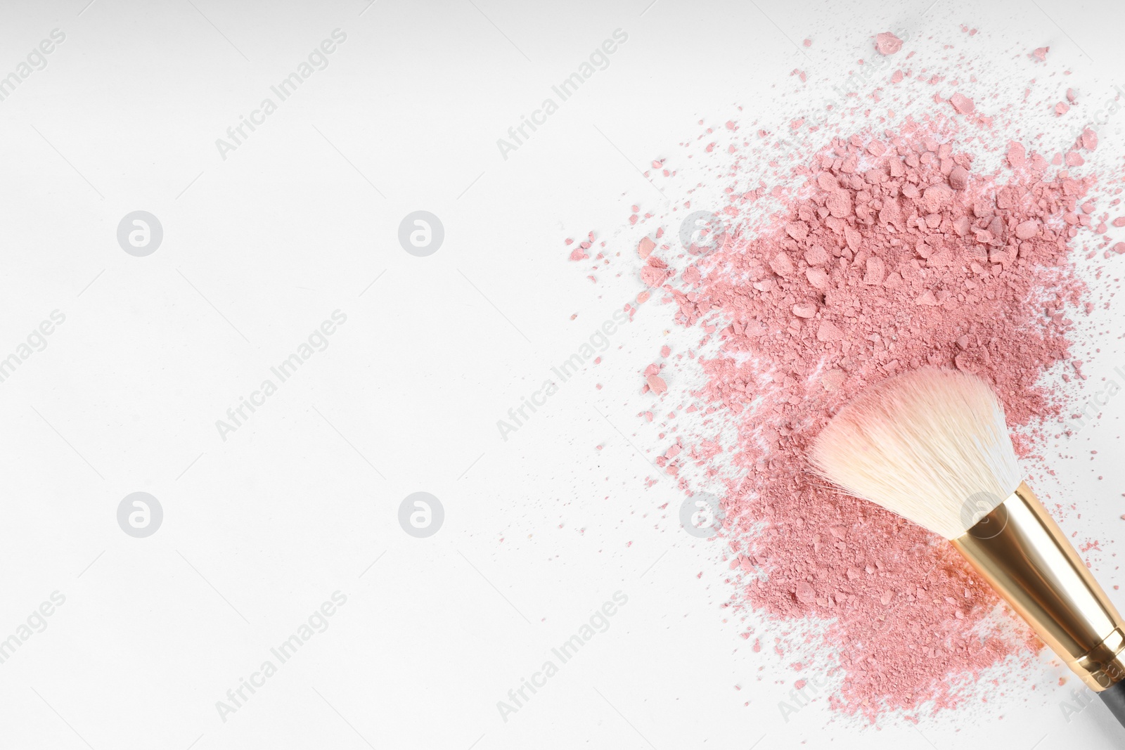 Photo of Makeup brush and scattered blush on white background, top view. Space for text