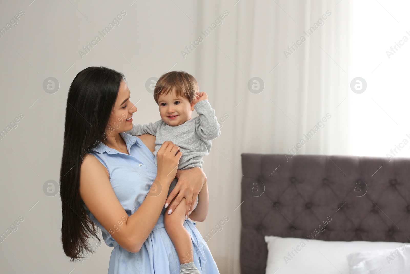 Photo of Young nanny with cute little baby in bedroom. Space for text