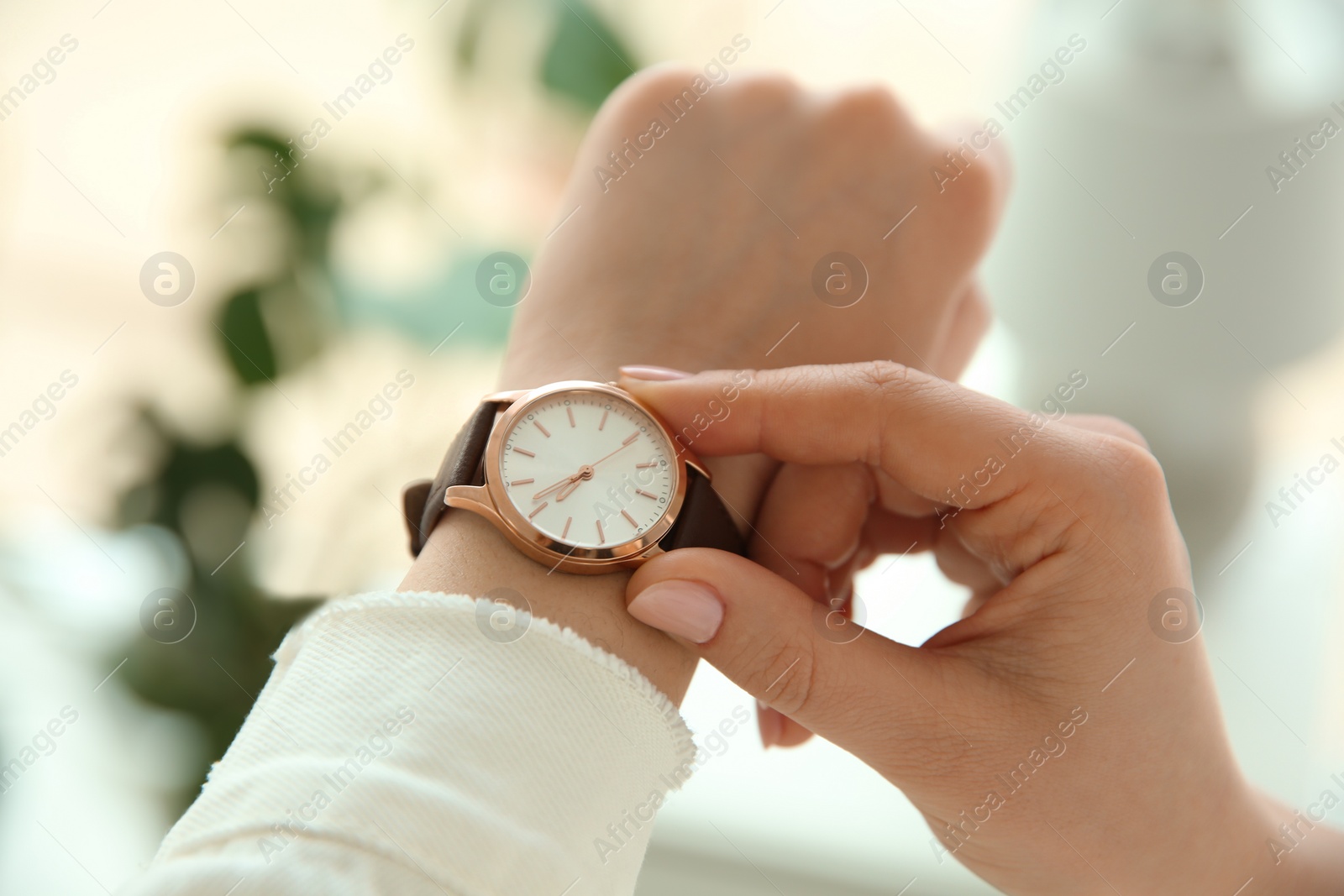 Photo of Woman with luxury wristwatch on blurred background, closeup