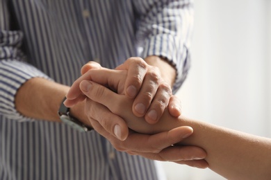 Photo of Man comforting woman on light background, closeup of hands. Help and support concept