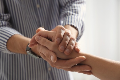 Man comforting woman on light background, closeup of hands. Help and support concept