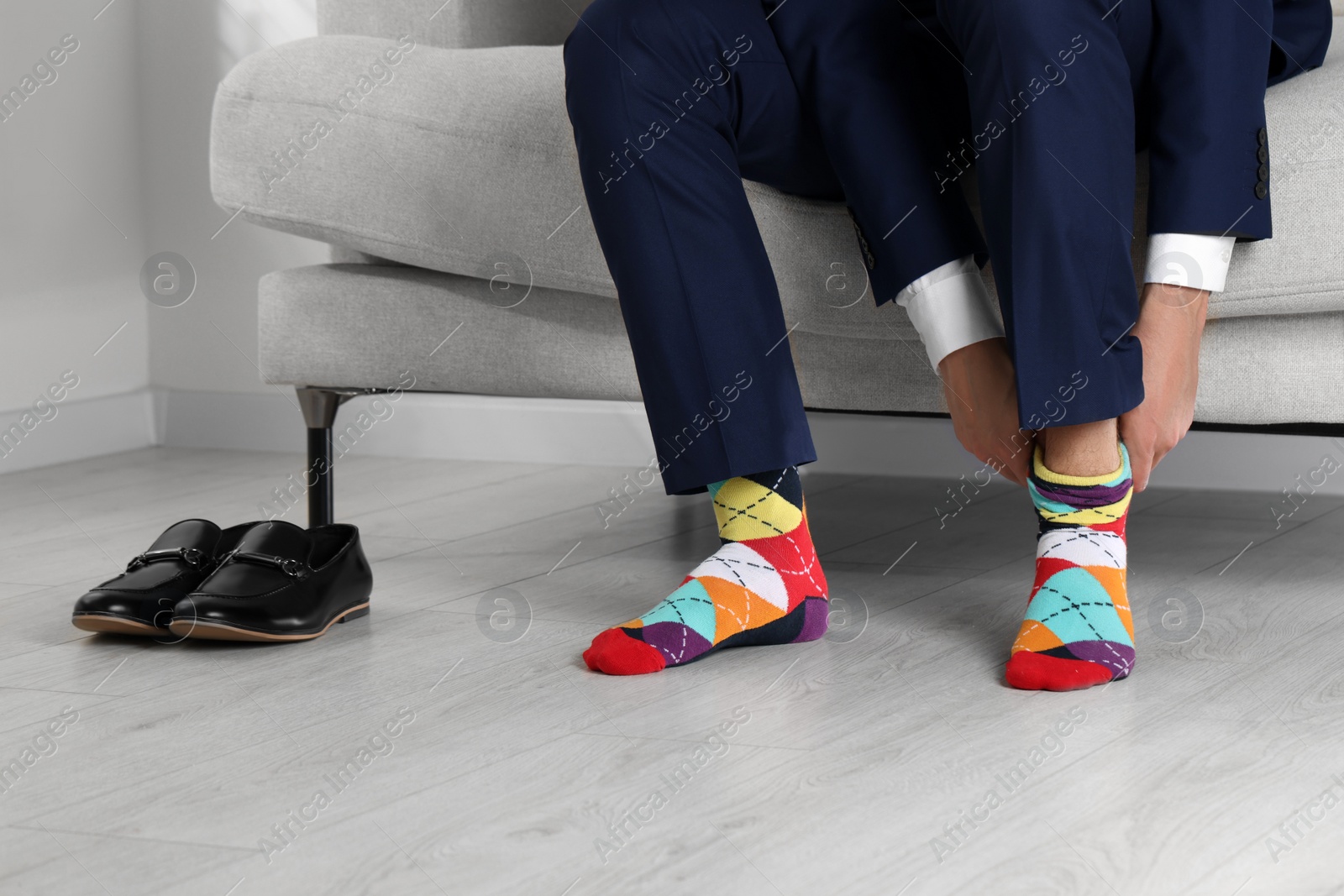 Photo of Man putting on colorful socks at home, closeup