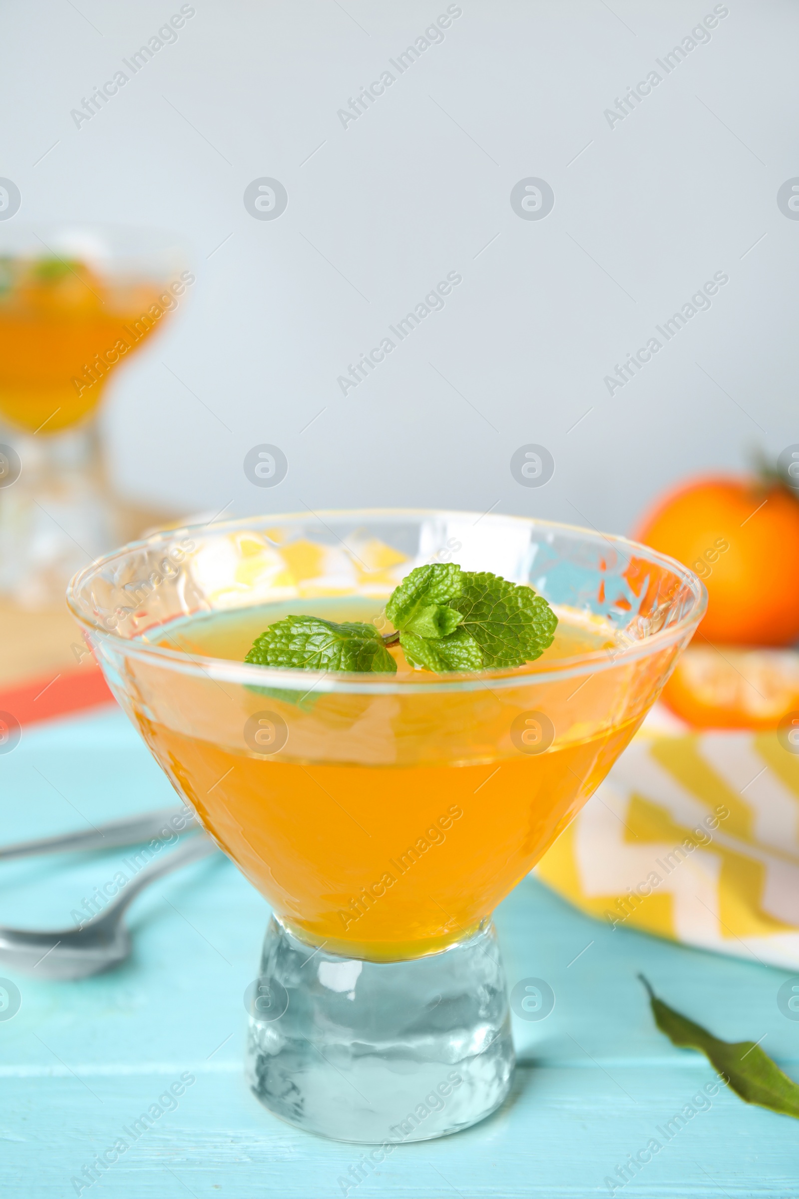 Photo of Delicious tangerine jelly on light blue wooden table, closeup