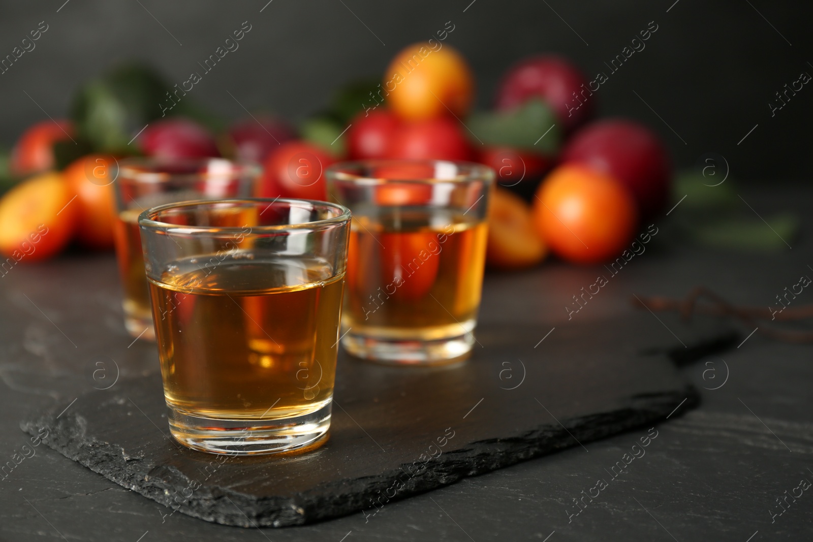 Photo of Delicious plum liquor on black table. Homemade strong alcoholic beverage