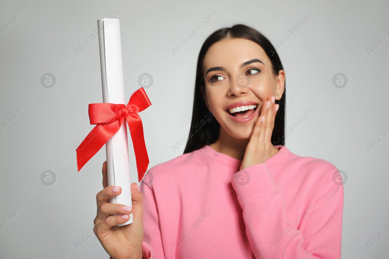 Photo of Emotional woman against light grey background, focus on diploma