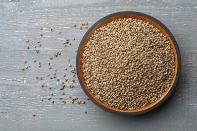 Photo of Organic hemp seeds on grey wooden table, top view. Space for text