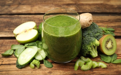 Photo of Green juice and fresh ingredients on wooden table, closeup