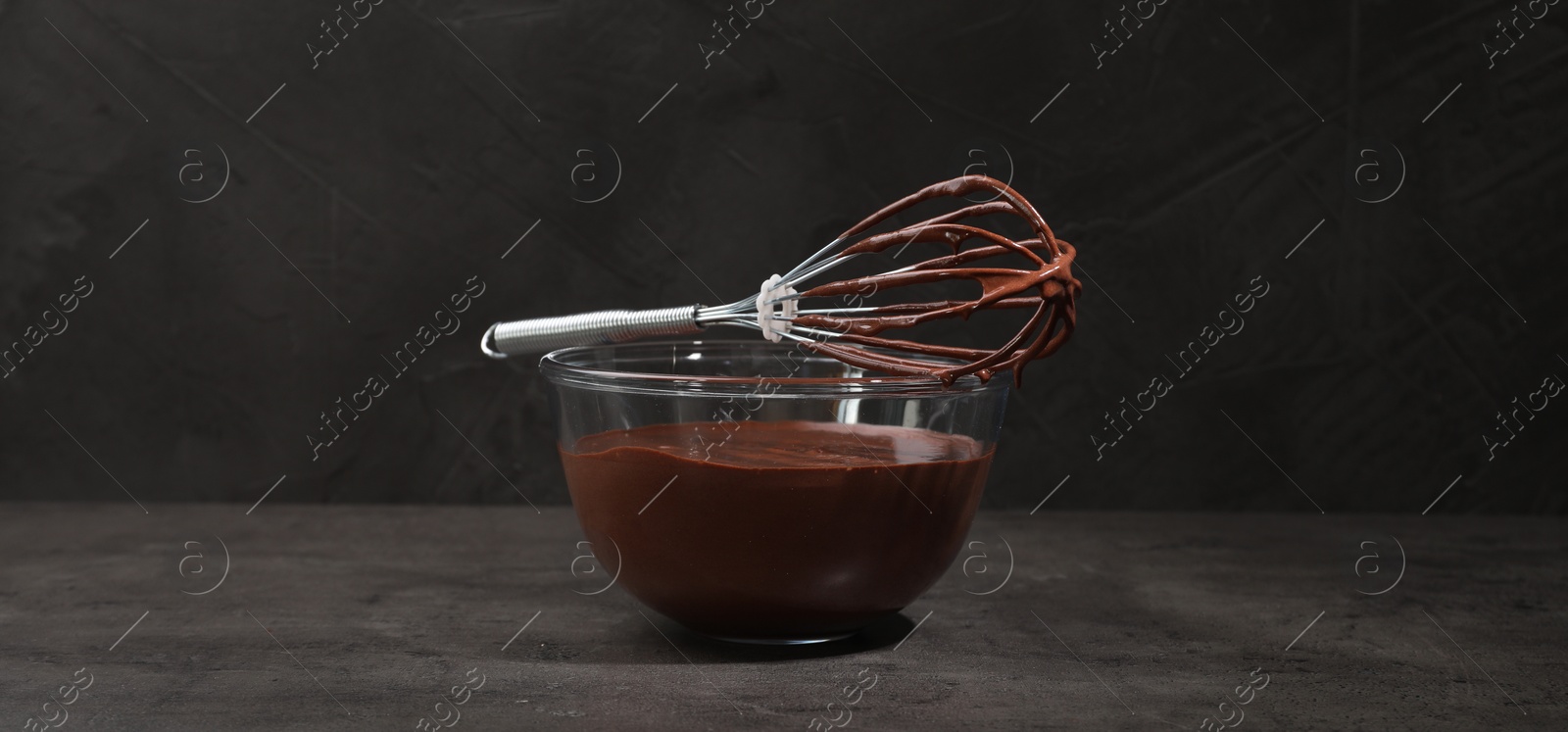 Image of Bowl and whisk with yummy chocolate cream on black table. Banner design