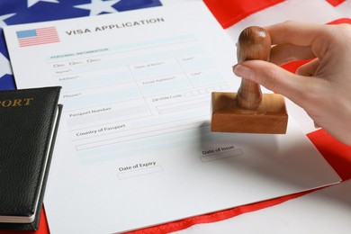 Photo of Immigration to USA. Woman stamping visa application form on flag, closeup