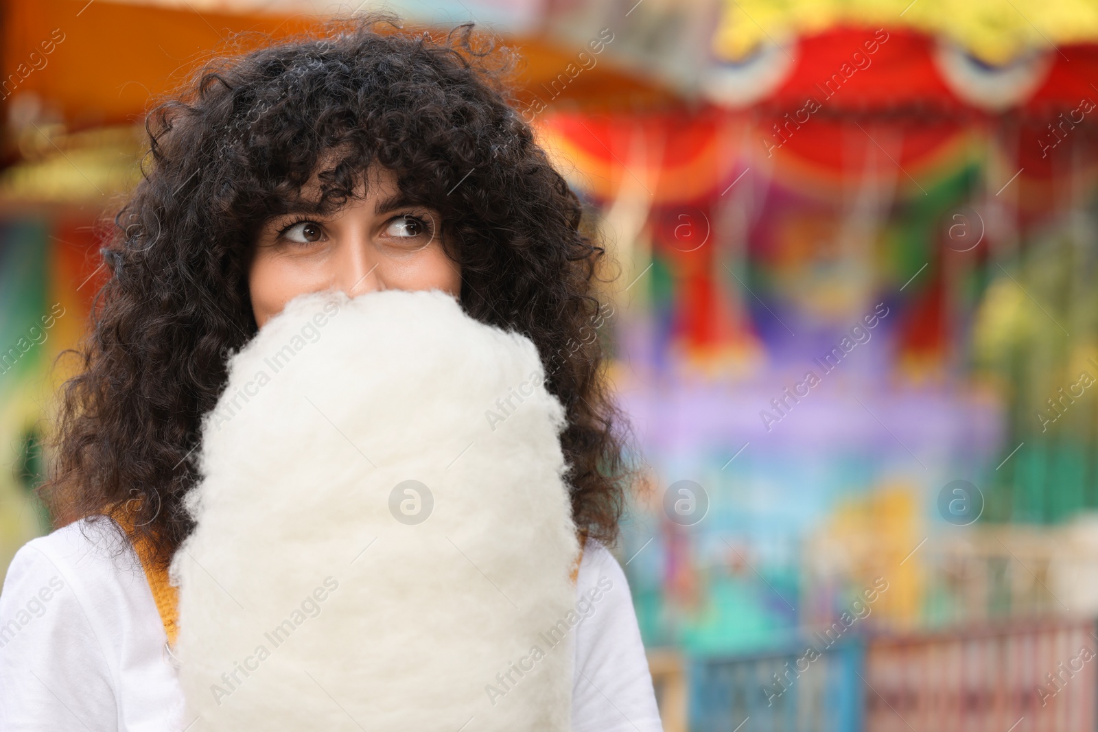 Photo of Beautiful woman with cotton candy at funfair. Space for text