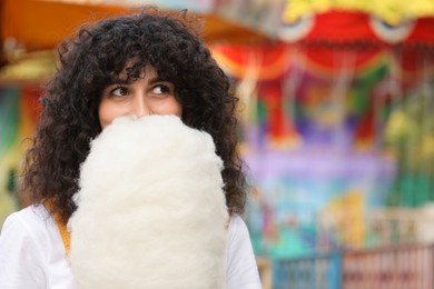 Beautiful woman with cotton candy at funfair. Space for text