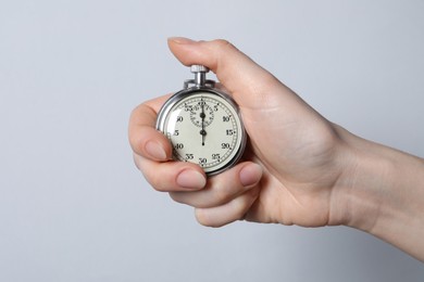 Photo of Woman holding vintage timer on light grey background, closeup