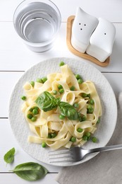 Delicious pasta with green peas served on white wooden table, flat lay