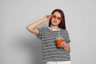 Photo of Beautiful young woman with plastic cup of juice on light grey background