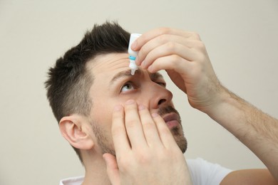 Photo of Man using eye drops on beige background