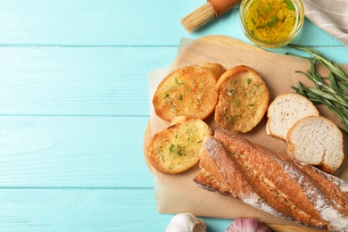 Slices of toasted bread with garlic and herbs on light blue wooden table, flat lay. Space for text