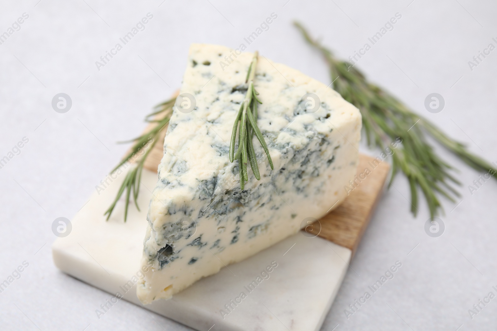 Photo of Tasty blue cheese with rosemary on light table, closeup