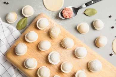 Flat lay composition with raw dumplings on grey background. Process of cooking