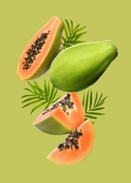 Image of Fresh papaya fruits and leaves falling on light green background