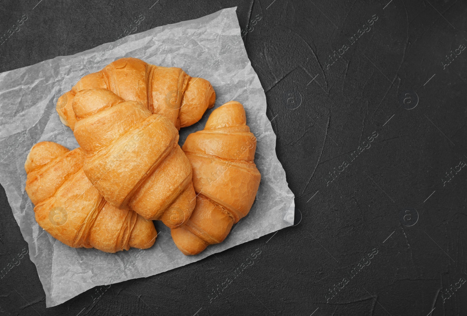 Photo of Tasty croissants on dark background, top view