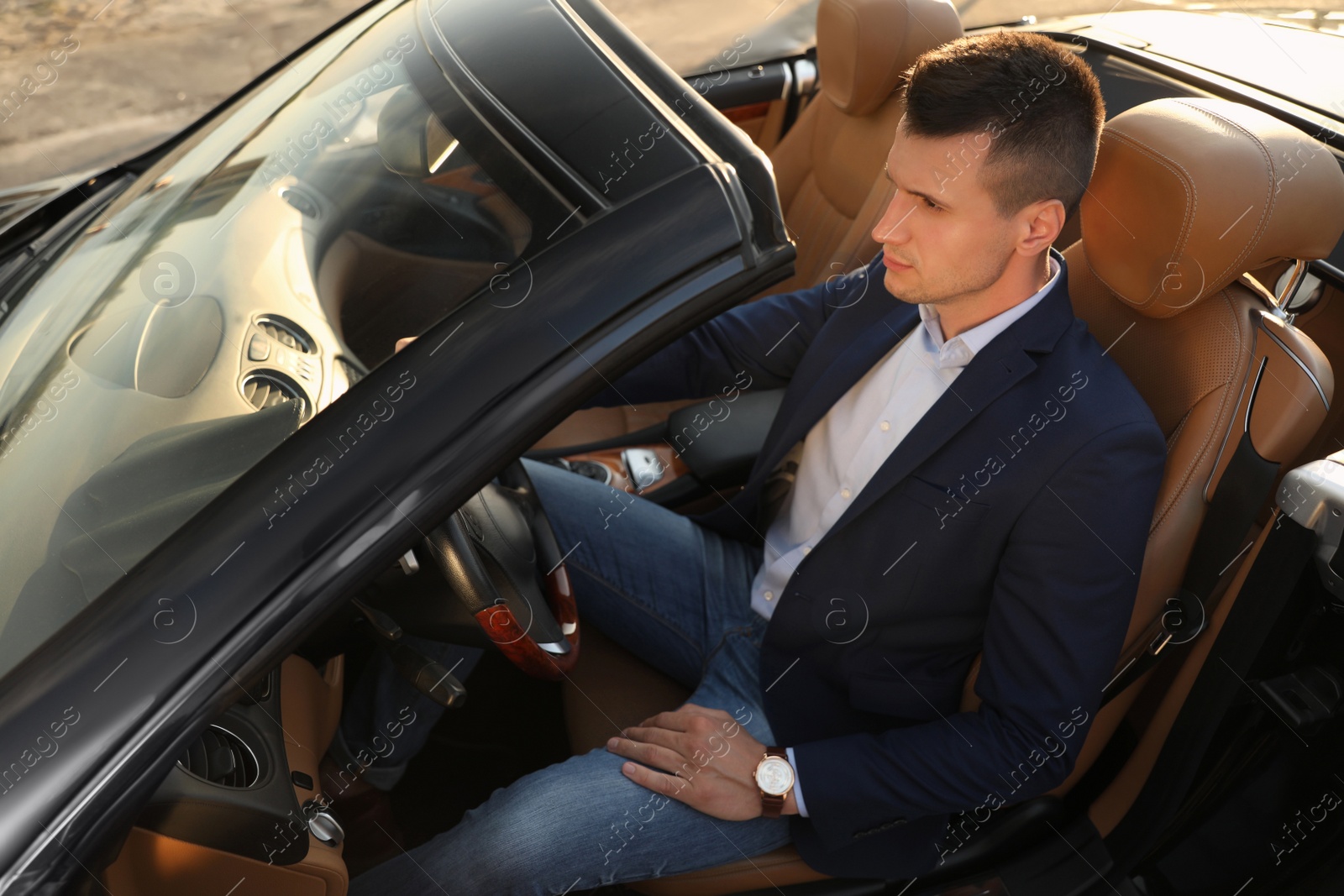 Photo of Young businessman in luxury convertible car outdoors