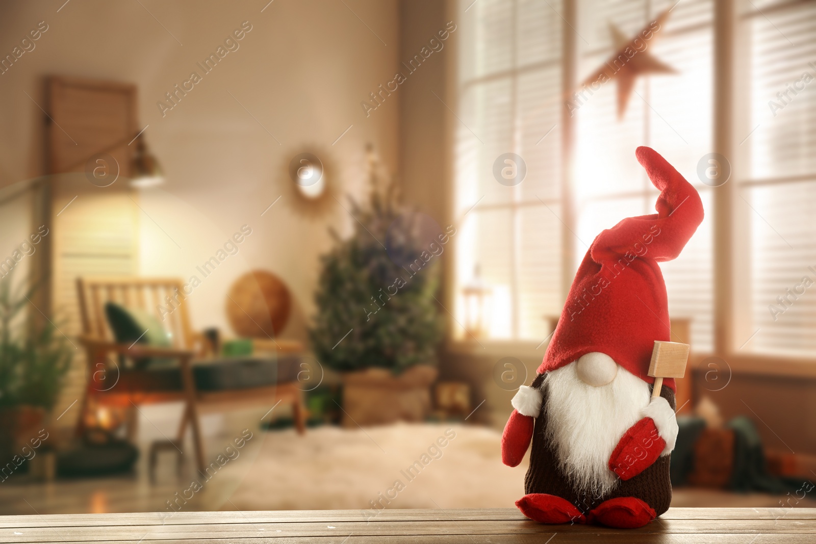 Image of Funny Christmas gnome on wooden table in room with festive decorations. Space for text
