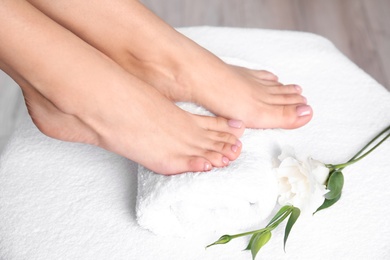 Photo of Woman with smooth feet on white towel, closeup. Spa treatment