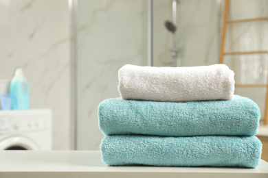 Photo of Stack of clean towels on table in laundry room. Space for text