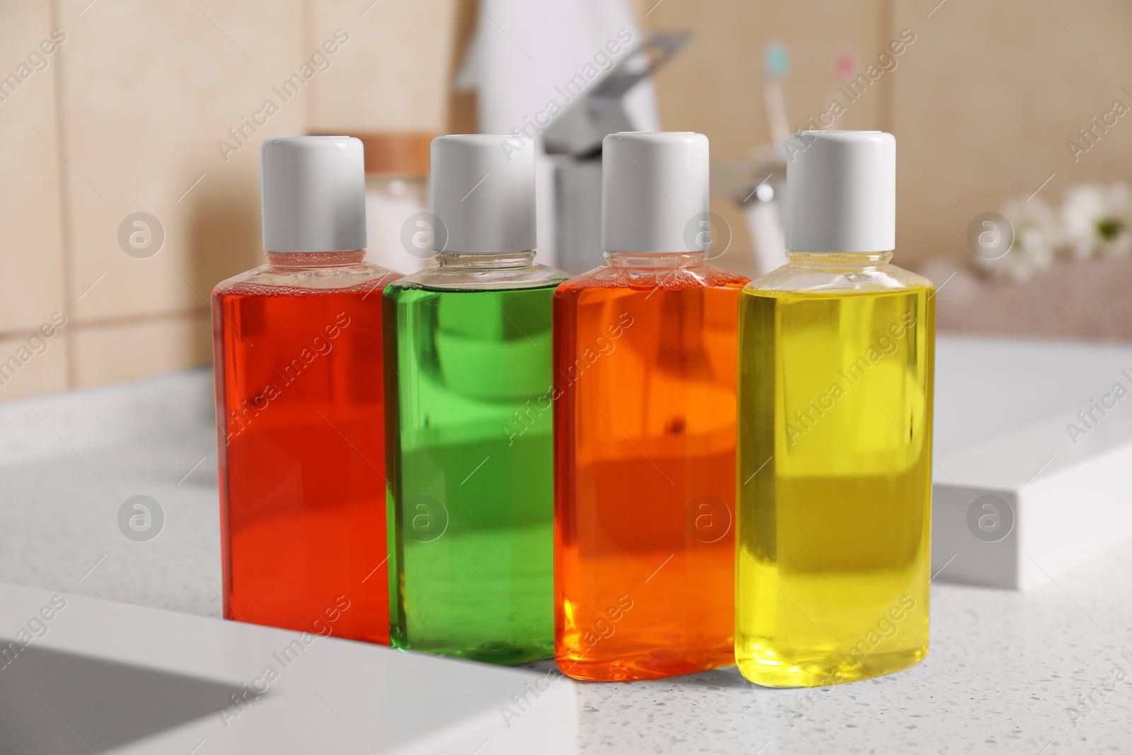 Photo of Fresh mouthwashes in bottles on countertop in bathroom, closeup