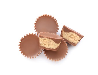 Cut and whole delicious peanut butter cups on white background, top view