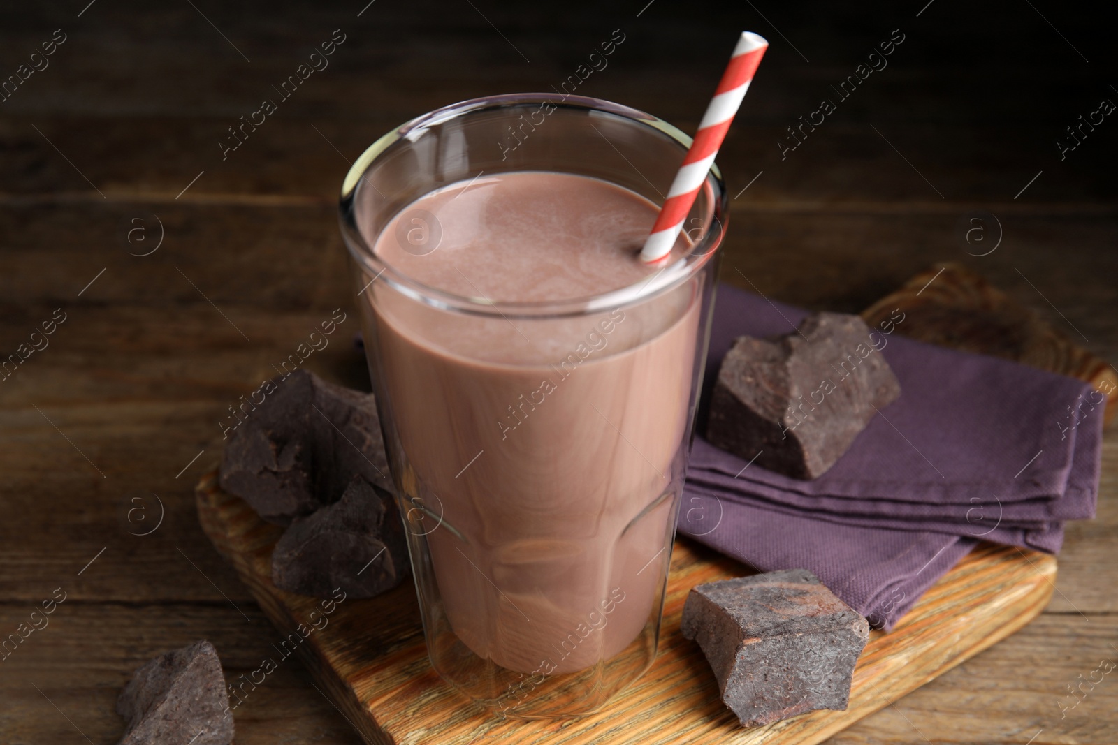 Photo of Delicious chocolate milk in glass on wooden table