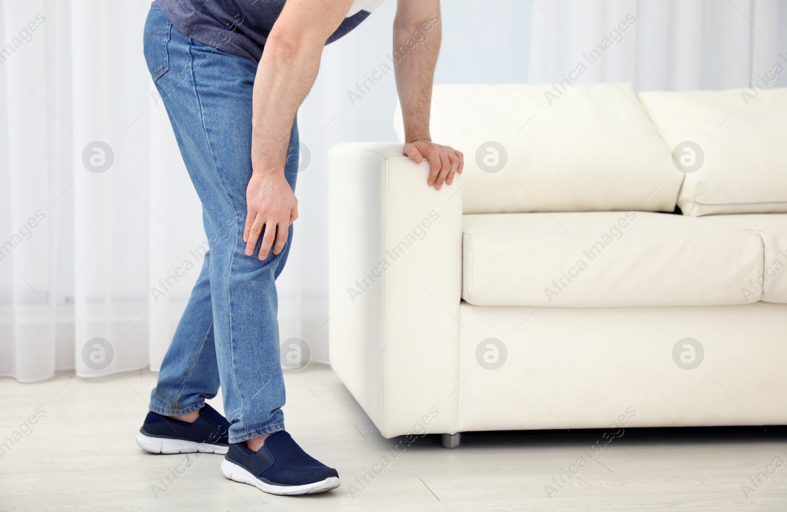 Photo of Young man suffering from leg pain indoors, closeup. Space for text