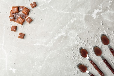 Photo of Flat lay composition with tasty caramel candies and sauce on light background