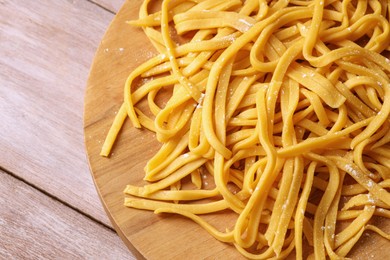 Photo of Board with homemade pasta on wooden table, top view. Space for text