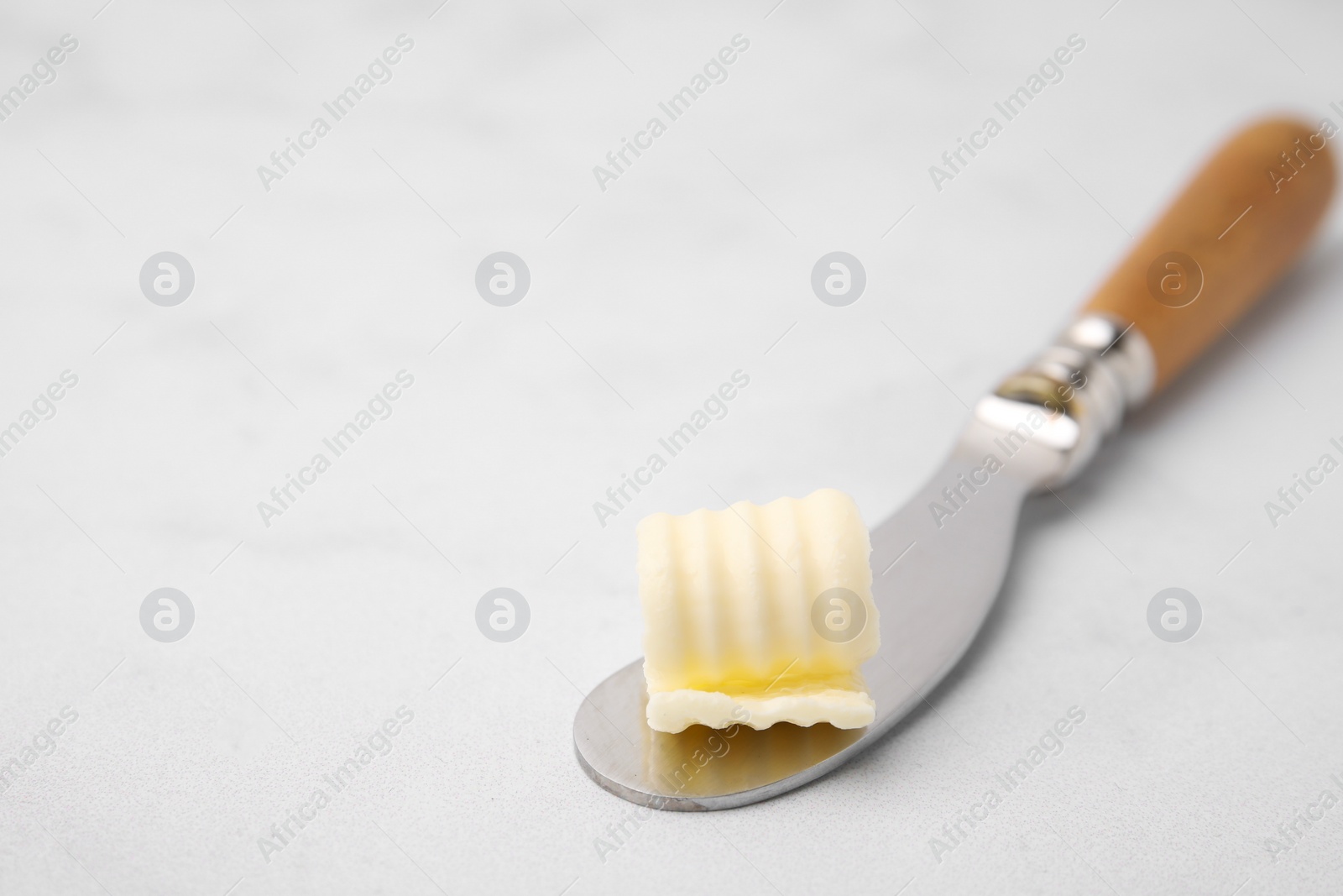 Photo of Tasty butter curl and knife on white table, closeup. Space for text