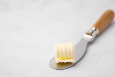 Photo of Tasty butter curl and knife on white table, closeup. Space for text