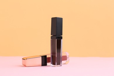 Photo of Two lip glosses on pink and orange background