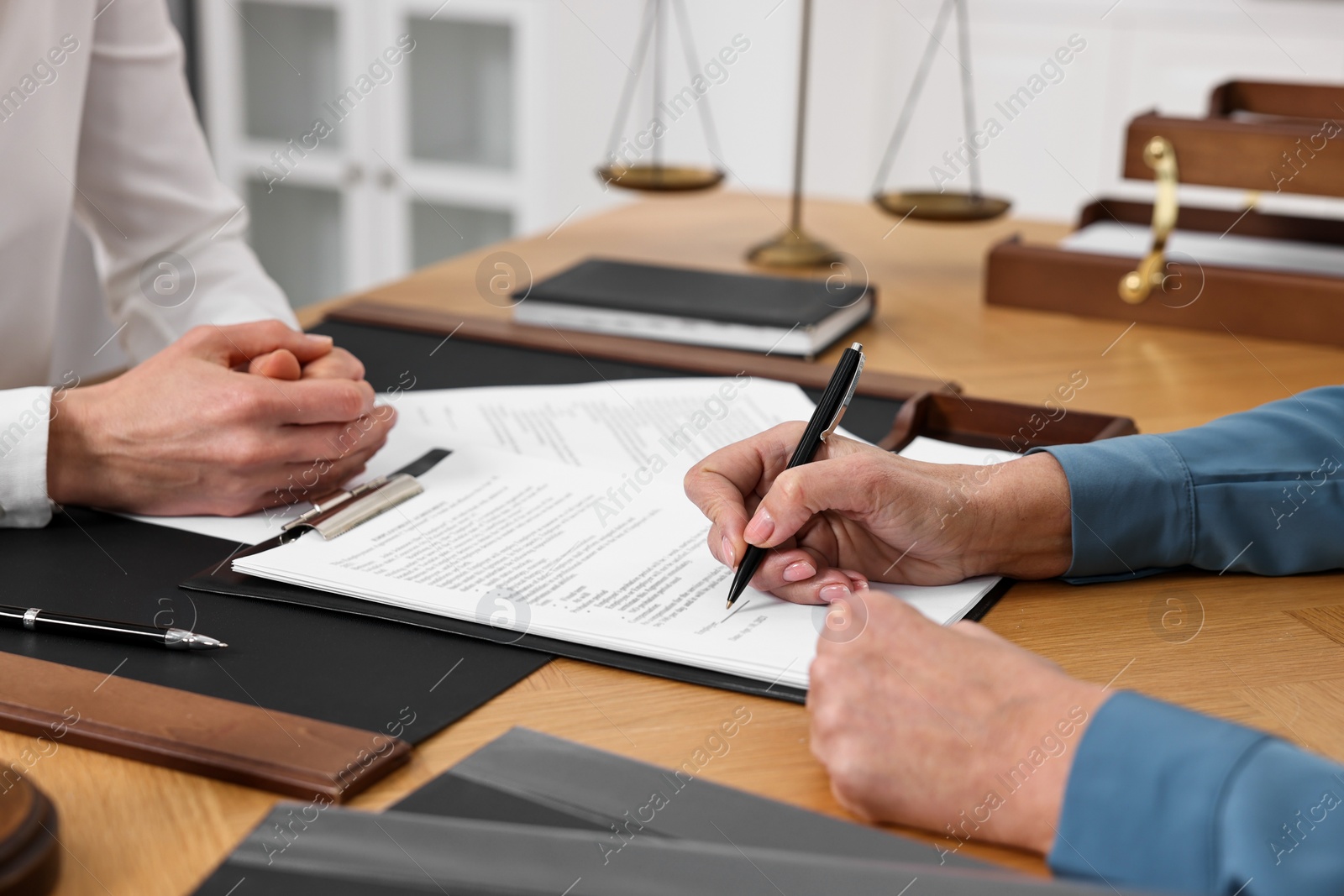 Photo of Senior woman signing document in lawyer's office, closeup