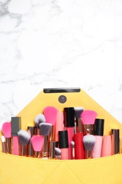 Photo of Different makeup products in cosmetic bag on white marble table, top view. Space for text